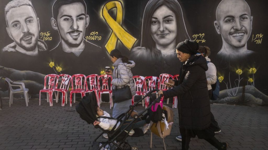 People walk and jog past an installation and a mural of portraits of hostages held by Hamas in the Gaza Strip, in Jerusalem, Friday, Jan. 24, 2025.