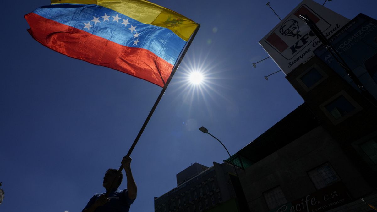 A man waves a flag during a protest by opponents of Venezuelan President Nicolas Maduro on the eve of his inauguration for a third term in Caracas