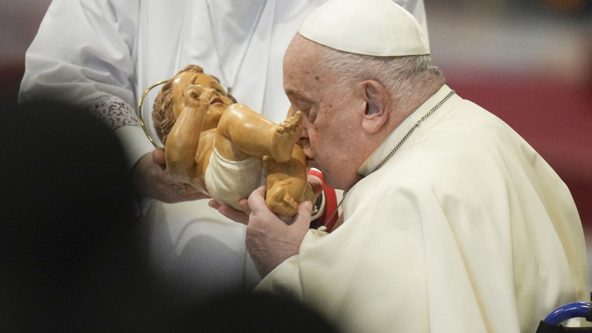 Pope Francis kisses the baby Jesus as he presides over an Epiphany mass in St.Peter