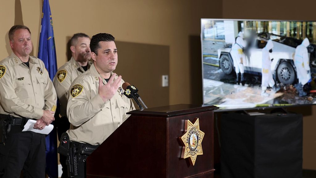 An assistant sheriff shows a photo of the investigation into a Tesla Cybertruck that exploded at a Trump hotel during a press briefing in Las Vegas.