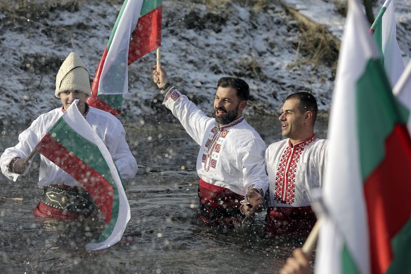 Les Bulgares chantent et dansent en tenant le drapeau bulgare dans la rivière Lesnovska lors des célébrations de l'Épiphanie dans la ville d'Elin Pelin, en Bulgarie, le lundi 6 janvier 2025.