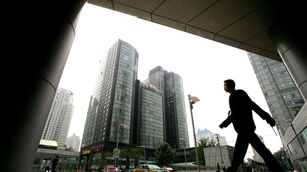 A man walks past new commercial buildings in Beijing.