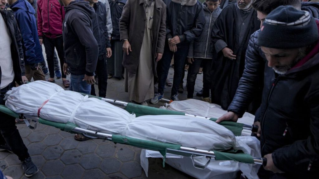 Palestinians carry the body of a relative killed in the Israeli bombardment of the Gaza Strip at Al-Aqsa Hospital in Deir Al-Balah, Tuesday, Jan. 14, 2025