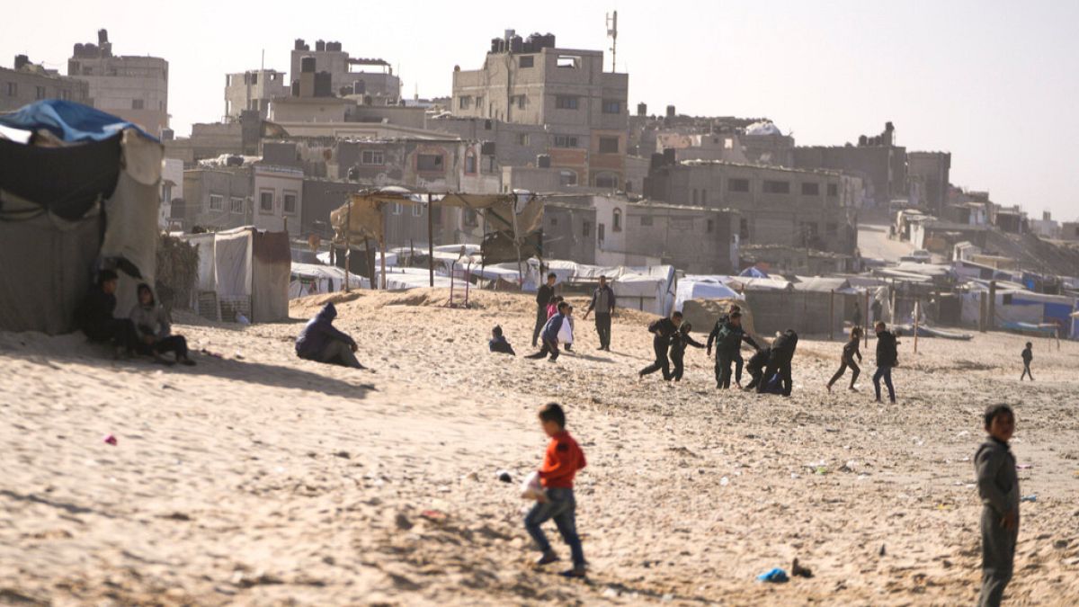 Children play on the sand in a camp for internally displaced Palestinians at the beachfront in Deir al-Balah, central Gaza Strip, Friday, Dec. 27, 2024.