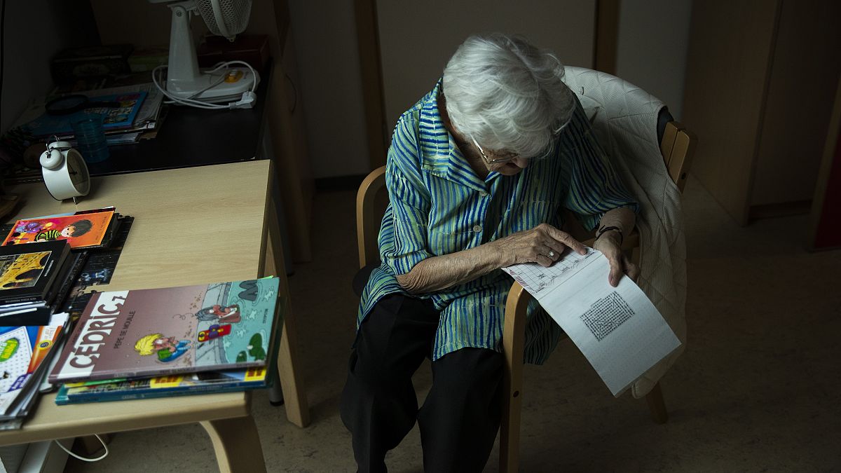 An older women works on a crossword puzzle at a home for elderly people in Belgium in July 2020.