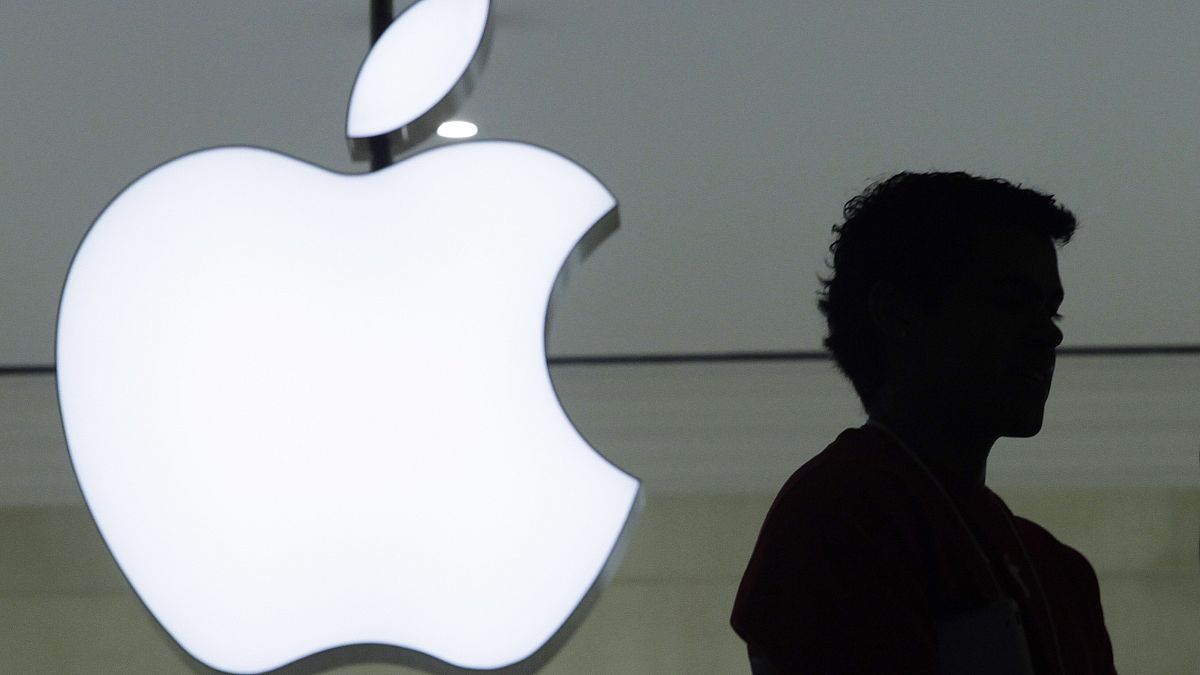 A person stands near the Apple logo at the company