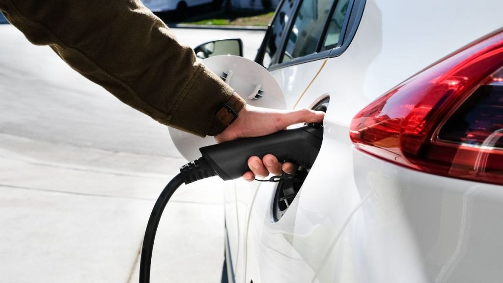 A person charging an electric vehicle (EV).