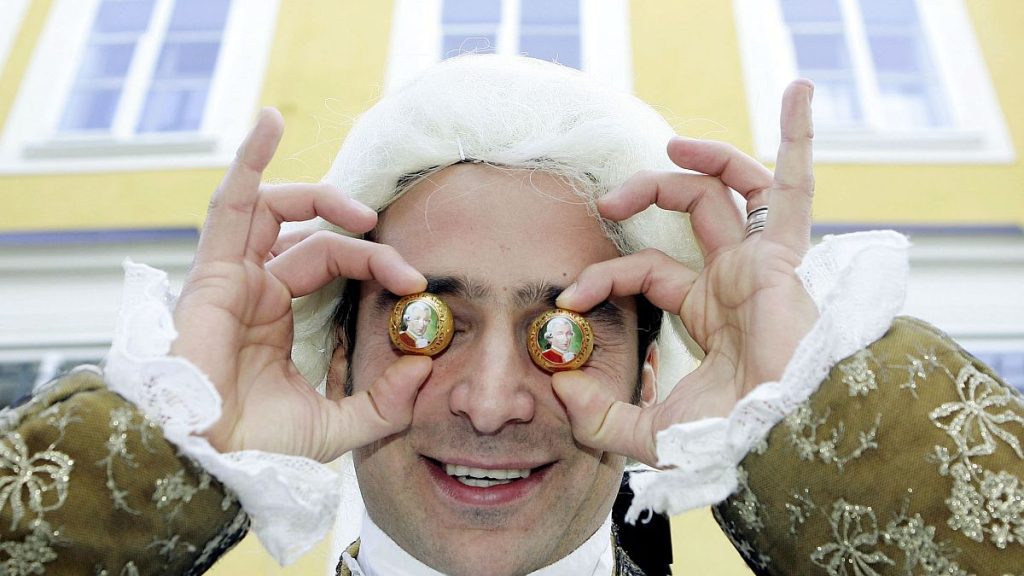 Benjamin Dzialowski, dressed up as Mozart holds Mozart balls against his eyes in front of Mozart