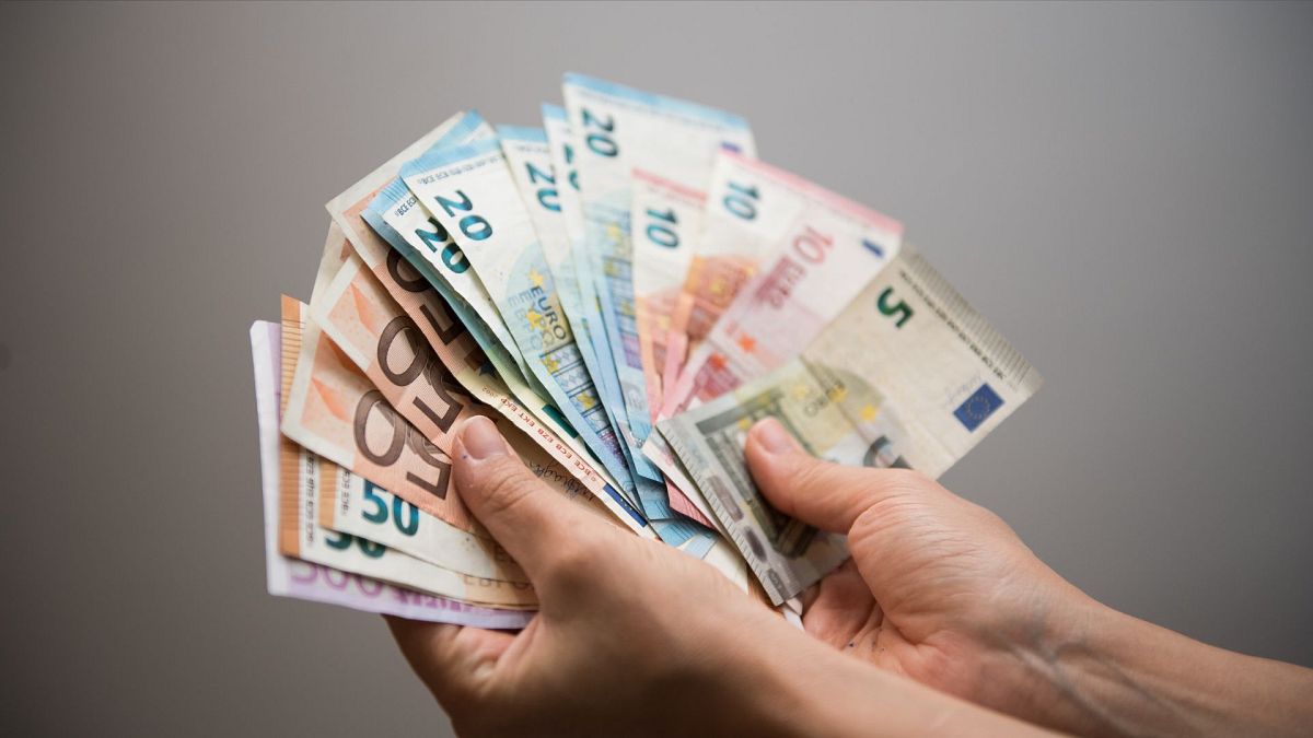 A person holding several euro notes