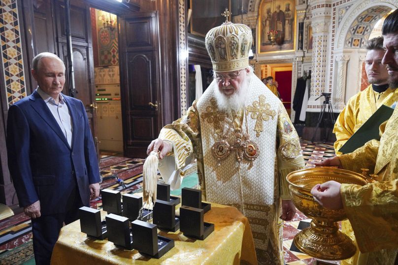 Le patriarche orthodoxe russe Kirill, au centre, accompagné du président russe Vladimir Poutine, à gauche, sanctifie les colliers de croix destinés aux militaires russes après la messe de Noël.