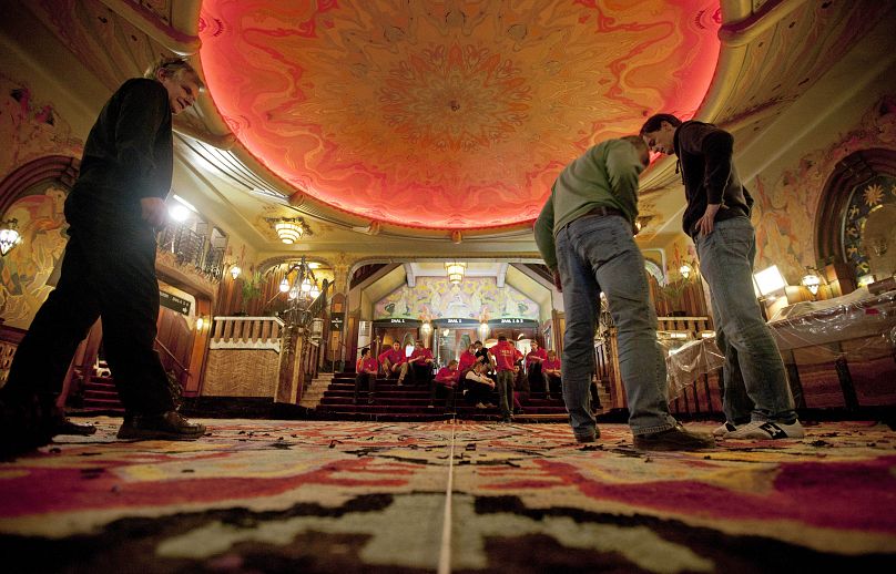 Des ouvriers apportent la touche finale à un nouveau tapis à l'entrée du palais du cinéma Art déco Tuschinski à Amsterdam, aux Pays-Bas, le vendredi 13 janvier 2012.