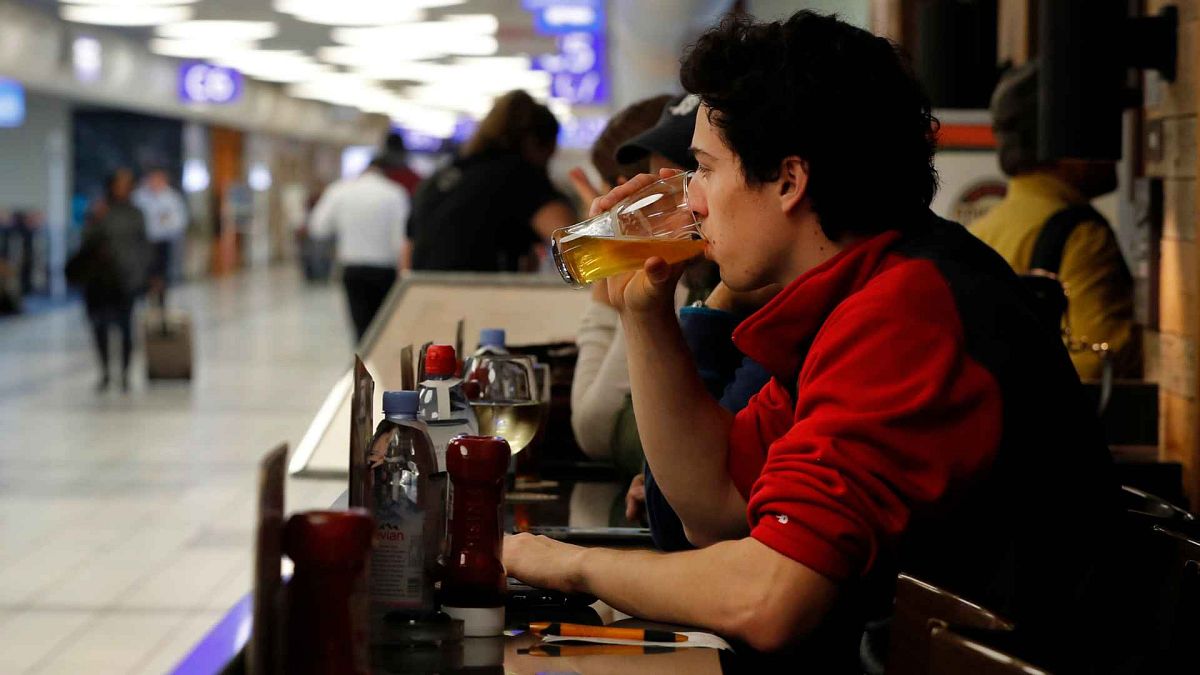 A passenger sips on a beer while waiting to board a flight at St. Louis Lambert International Airport in St. Louis.