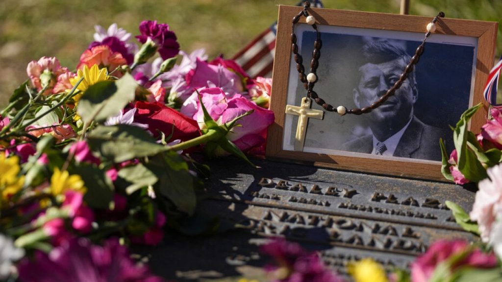 FILE - A rosary covers a photograph of President John F. Kennedy at a marker along Elm Street, Dallas, Nov. 22, 2023