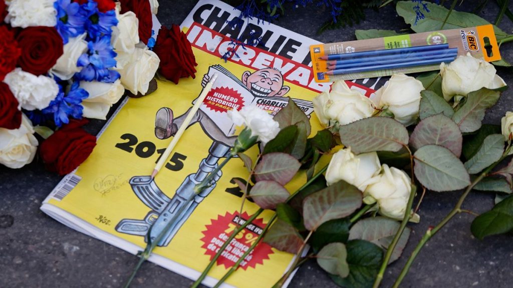 A special edition of French satirical newspaper Charlie Hebdo lays amid wreaths and pencils left in front of Charlie Hebdo