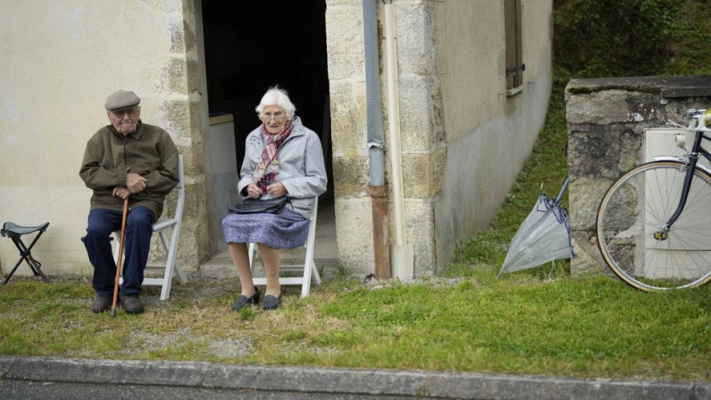 Two spectators wait for the peloton to pass during the eleventh stage of the Tour de France cycling race in Normandy, Wednesday, July 10, 2024.