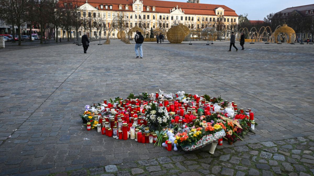 Flowers and candles are seen on a place of remembrance for the victims of the attack at Christmas market on the cathedral square with the Saxony-Anhalt parliament building.