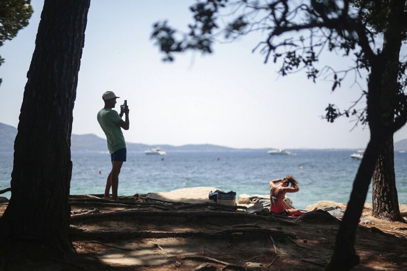 Un touriste prend des photos sur la plage de Pollença, sur l'île Baléares de Majorque, Espagne, le mardi 28 juillet 2020.