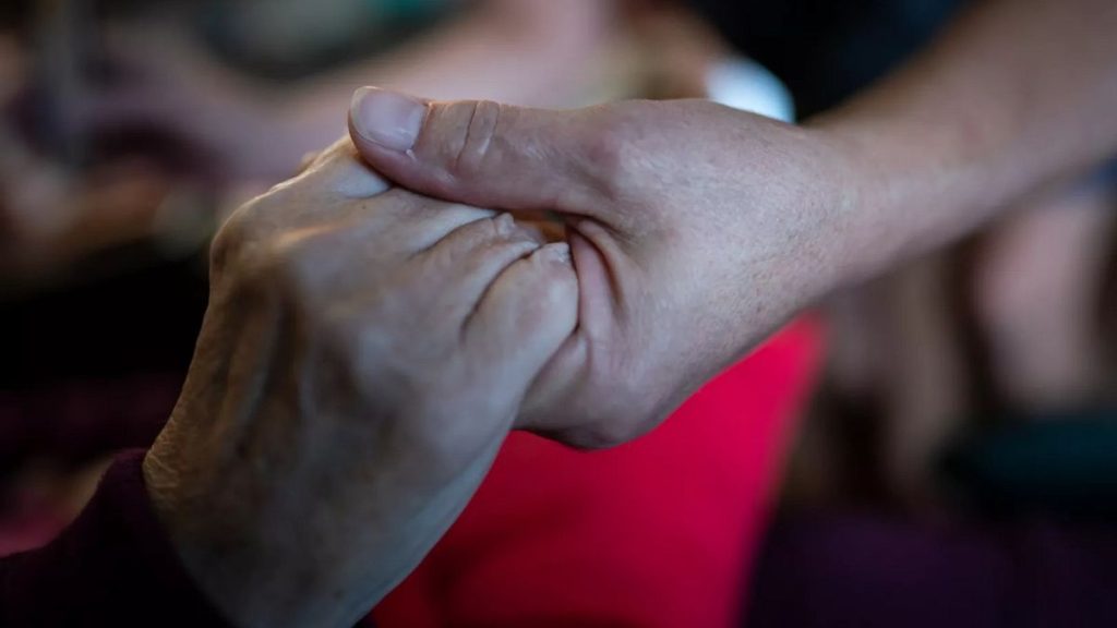 An elderly woman holds hands with her daughter in this 2021 file photo.