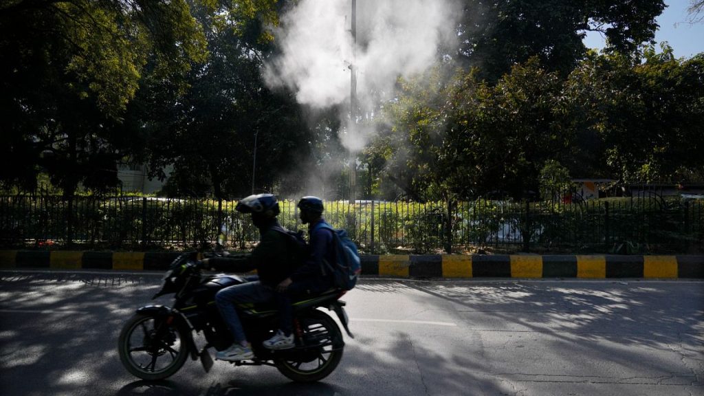 A motorcyclist drives past sprinklers that spray water in hopes of settling dust and calming air pollution in New Delhi, Feb. 12, 2025.